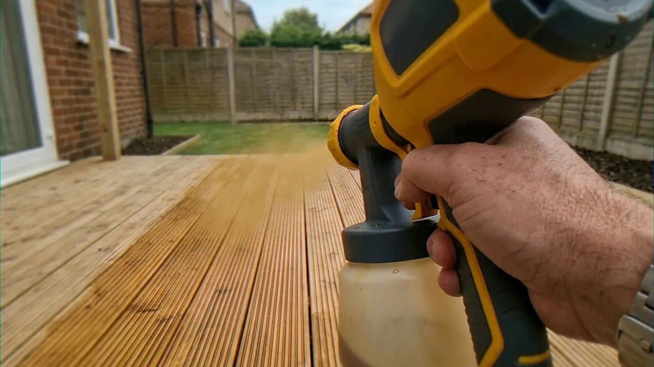 Spraying decking oil along the length of a deck board with an HVLP sprayer
